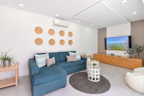 A modern living room with a sectional sofa, a round coffee table, and a flat-screen TV mounted on the wall. - Cosy Bungalow for 6 in Playa del Ingles GD04 (San Bartolomé de Tirajana)