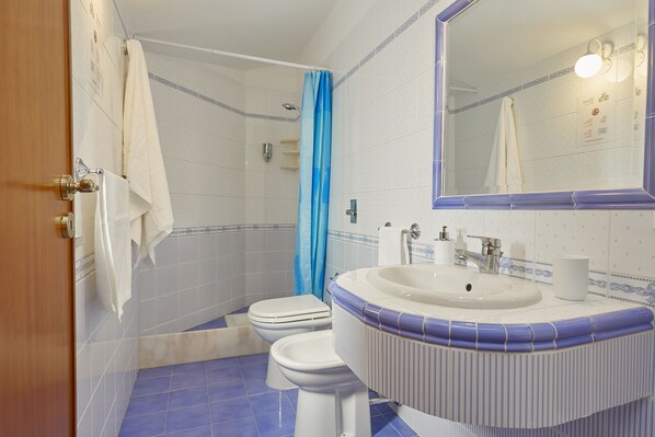 Un baño con inodoro, lavabo y ducha.