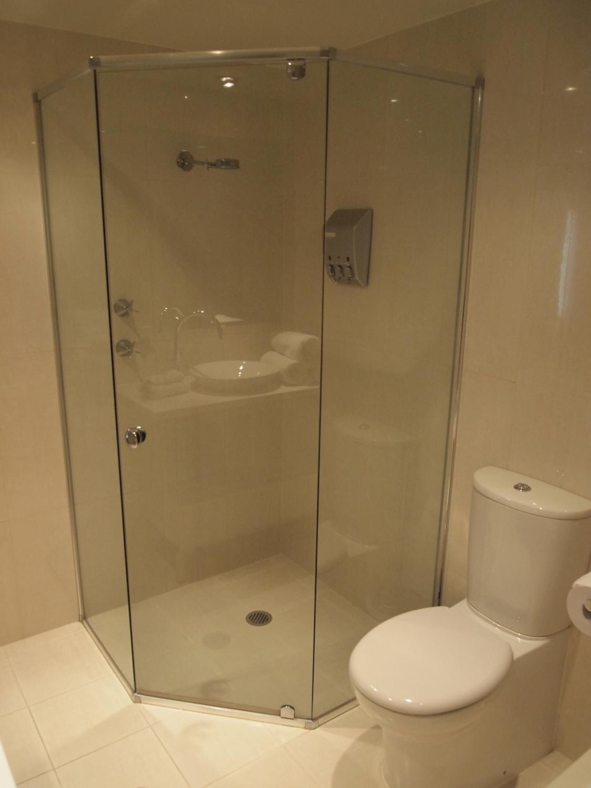 A glass-enclosed shower stall with a toilet to the right.