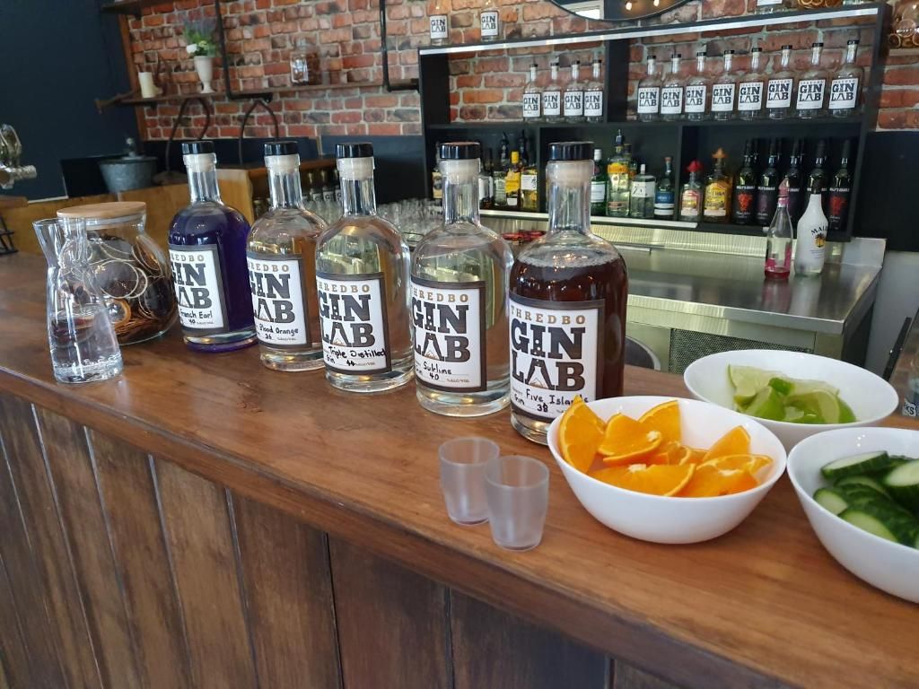 A bar counter with several bottles of gin, a pitcher, and bowls of fruit.