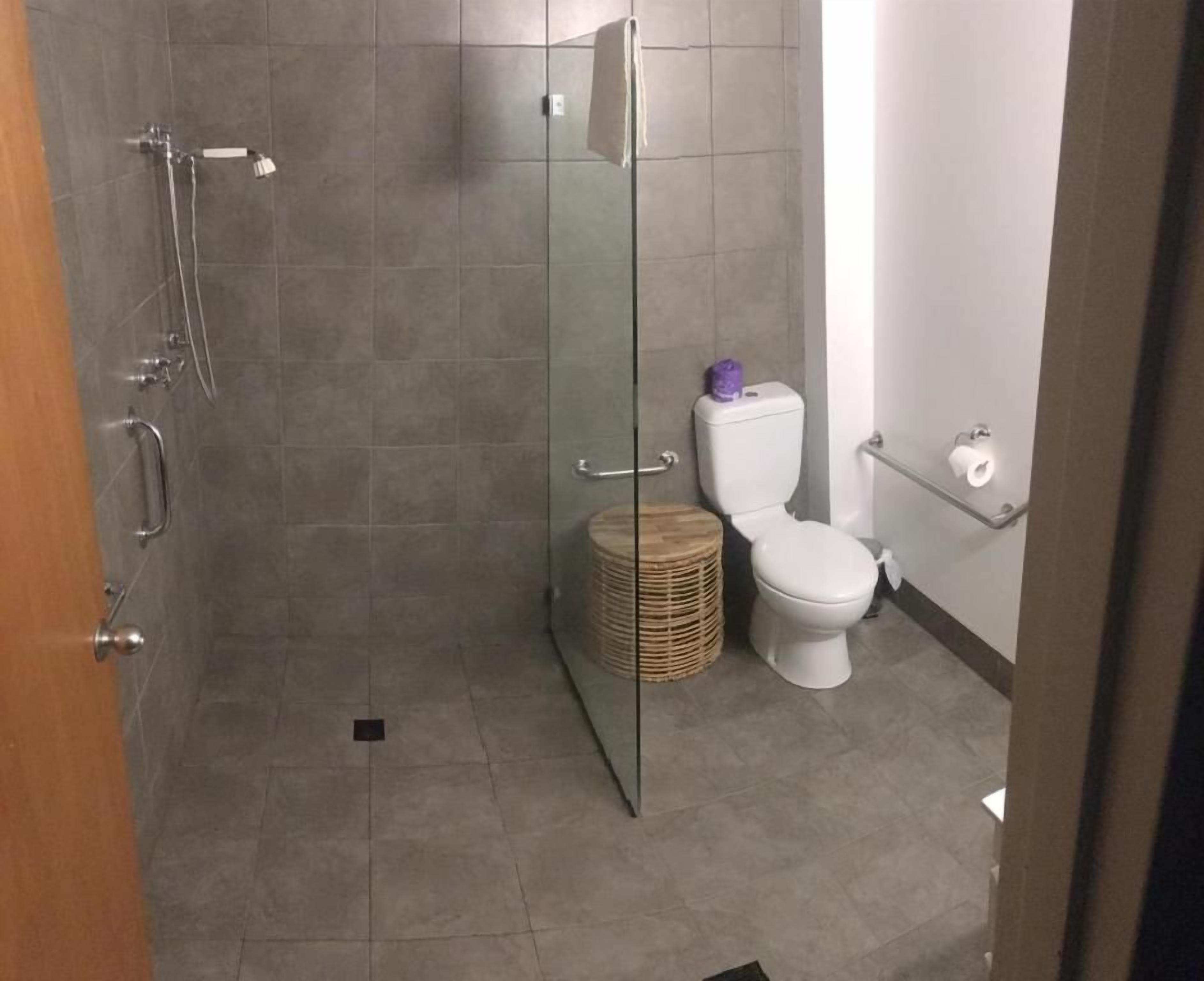 A bathroom with a shower, toilet, and a wicker basket.