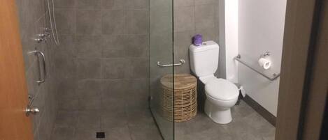 A bathroom with a shower, toilet, and a wicker basket.