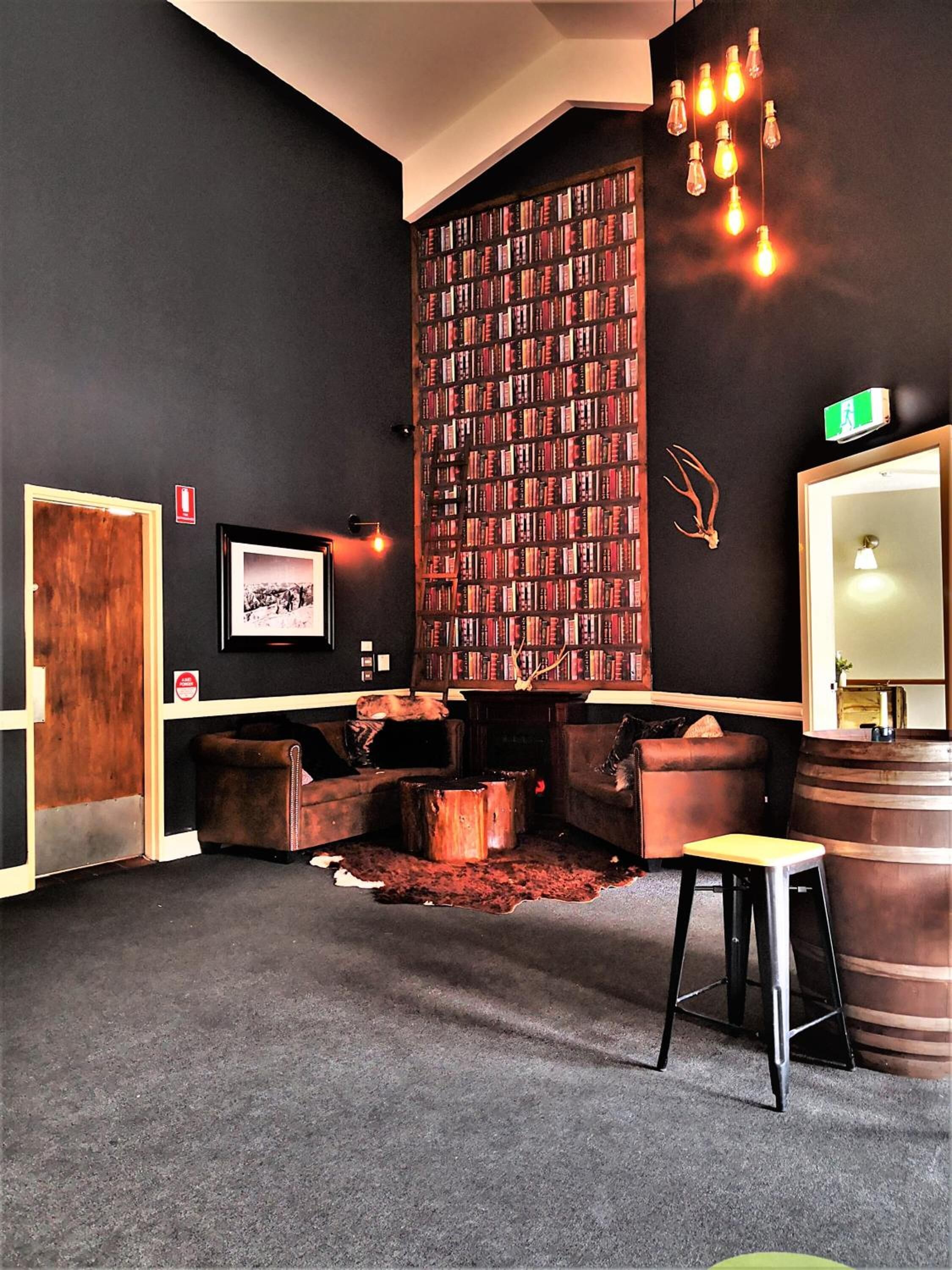 Un coin lecture confortable avec une bibliothèque, des canapés en cuir, une petite table et un tonneau en bois.