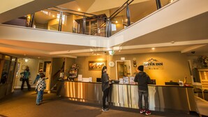 A hotel reception area with a modern design, a visible clock, and a sign for the River Inn. - The River Inn Thredbo (Thredbo)