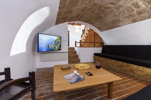 Relax in a cozy space with a wooden table, television, and cushioned seating area.