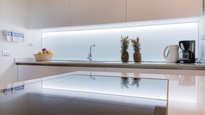 A modern kitchen with a glass-top island, a stainless steel sink, and a coffee maker.