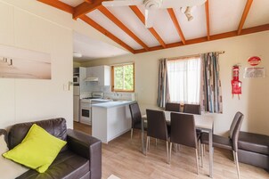 Un espacio habitable compacto con kitchenette, comedor y un sofá con un cojín luminoso.