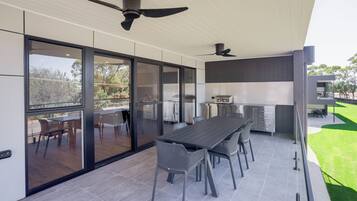 A modern kitchen with a dining area, large windows, and ceiling fans.