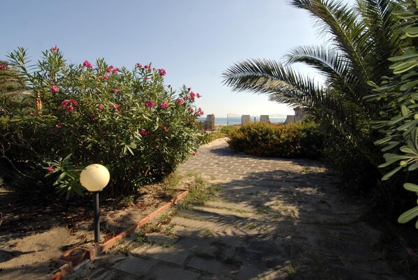 A paved pathway with a lamp post and flowering plants. - Villa with direct access to the beach between Catania and Syracuse (Carlentini)