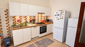 Eine Küche mit weißen Schränken, einem Herd, einer Spüle und einem Kühlschrank.
