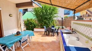 Une terrasse avec une table et des chaises, un petit jardin et une salle de bain avec une baignoire.