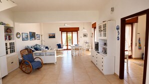 A spacious living area with a sofa, dining table, and white cabinets.