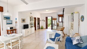 A spacious living area with a dining table, sofa, and a television.