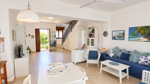 Ein großzügiger Wohnbereich mit einer Couch, Stühlen, einem Esstisch und einer Treppe, die zu einer oberen Etage führt.
