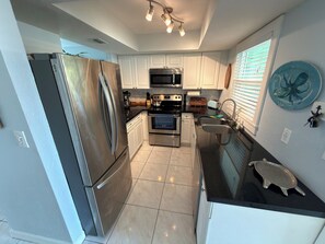 A modern kitchen with stainless steel appliances, white cabinetry, and a black countertop.