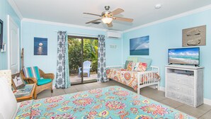 A room with a bed, a television, a ceiling fan, and a view of the outdoors. - BOUTIQUE BUNGALOW. INTIMATE TROPICAL SETTING. STEPS TO BEACH ACCESS. (Juno Beach)