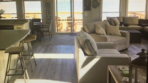 A spacious living area with a large sofa, a dining table with chairs, and a kitchen area. There are large windows providing natural light and a view of the outside. - *** NEWLY RENOVATED**** Escape to a Beautiful Getaway on the Chesapeake Bay (Perryville)