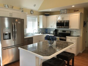 A modern kitchen with stainless steel appliances, white cabinetry, and a granite countertop.