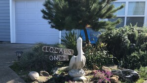 A garden with a sculpture, a 'Locals Only' sign, and a garage door in the background.