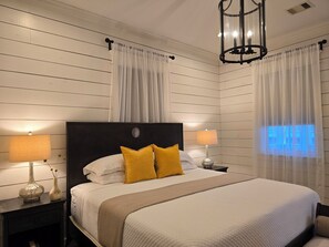 Une chambre à coucher bien aménagée, avec un grand lit, deux lampes de chevet, une table de chevet, un vase décoratif et un lustre moderne.