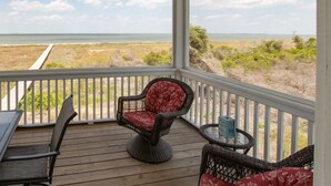 A covered porch with wicker chairs and a table, overlooking a beach and ocean. - VIEWS VIEWS VIEWS! BEACHFRONT 4 Bdrm Home.  Pvt Boardwalk to Beach. Golf cart! (St Helena Island)