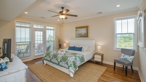 A bedroom with a bed, a chair, a ceiling fan, and a painting on the wall. - VIEWS VIEWS VIEWS! BEACHFRONT 4 Bdrm Home.  Pvt Boardwalk to Beach. Golf cart! (St Helena Island)