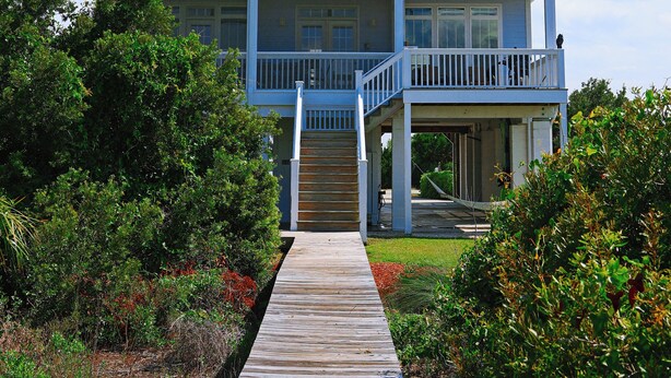 A two-story house with a wooden deck leading to the front door. - VIEWS VIEWS VIEWS! BEACHFRONT 4 Bdrm Home.  Pvt Boardwalk to Beach. Golf cart! (St Helena Island)