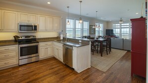 A modern kitchen with white cabinetry, stainless steel appliances, and a wooden floor. - VIEWS VIEWS VIEWS! BEACHFRONT 4 Bdrm Home.  Pvt Boardwalk to Beach. Golf cart! (St Helena Island)