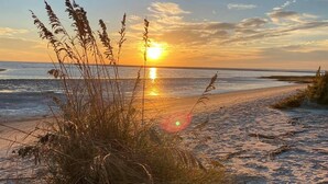A beach with tall grasses in the foreground and the sun setting over the ocean. - VIEWS VIEWS VIEWS! BEACHFRONT 4 Bdrm Home.  Pvt Boardwalk to Beach. Golf cart! (St Helena Island)