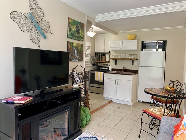 A living room with a TV, a fireplace, and a dining area with a table and chairs. - Bear House 1890, Sherfey Suite, Perfect Getaway, Walk to Cafes, Outdoor Activity (Chattanooga)