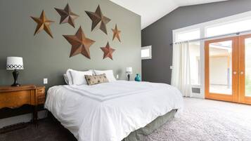 Une chambre avec un grand lit, un bureau et une fenêtre avec des rideaux.