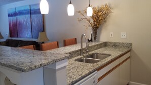 A kitchen with granite countertops, stainless steel sink, and overhead pendant lighting. - Harbor Springs -Trout Creek Unit  84, spacious 1700, VERY CLEAN, Building 12 (Harbor Springs)