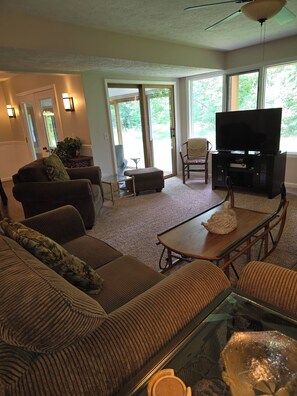 A living room with a sofa, ottoman, coffee table, and a television on a stand. - Fall Color Tour Trout Creek Unit  84, spacious 1700, VERY CLEAN, Building 12 (Harbor Springs)