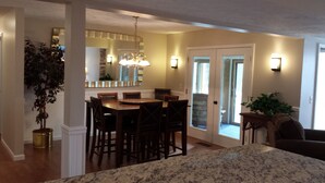 A dining area with a wooden table and chairs, a chandelier, and a view through a glass door to the outside. - Harbor Springs -Trout Creek Unit  84, spacious 1700, VERY CLEAN, Building 12 (Harbor Springs)