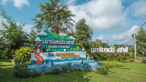 A colorful sign with Thai text and contact numbers, surrounded by lush greenery. - Mountain View House (Sangkhla Buri)