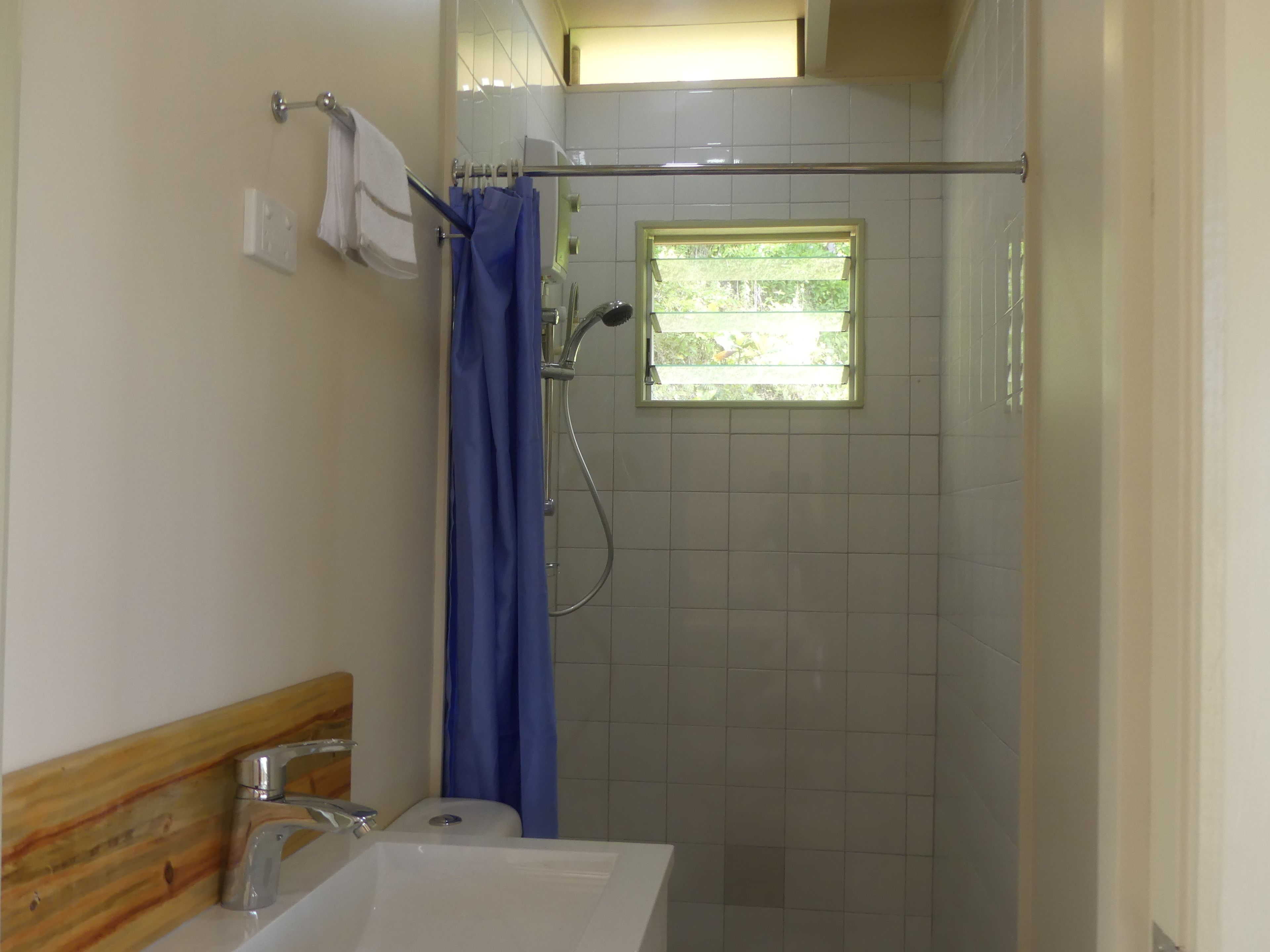 Un baño con ducha, ventana y lavamanos.