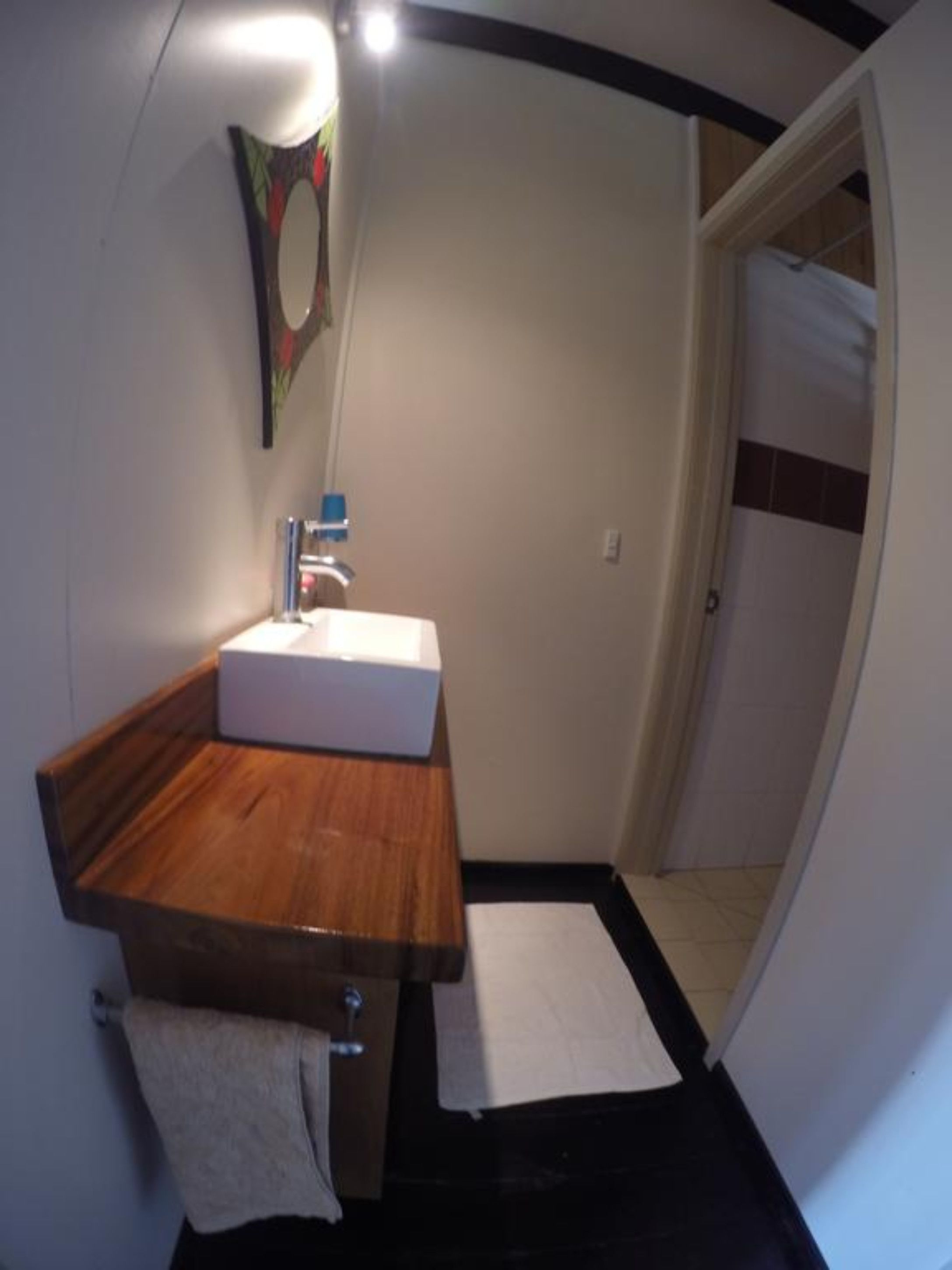 A bathroom with a wooden vanity, a white sink, and a towel hanging on the wall.
