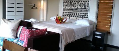 Una habitación de hotel con cama, armario, tapiz y ventana con persianas.