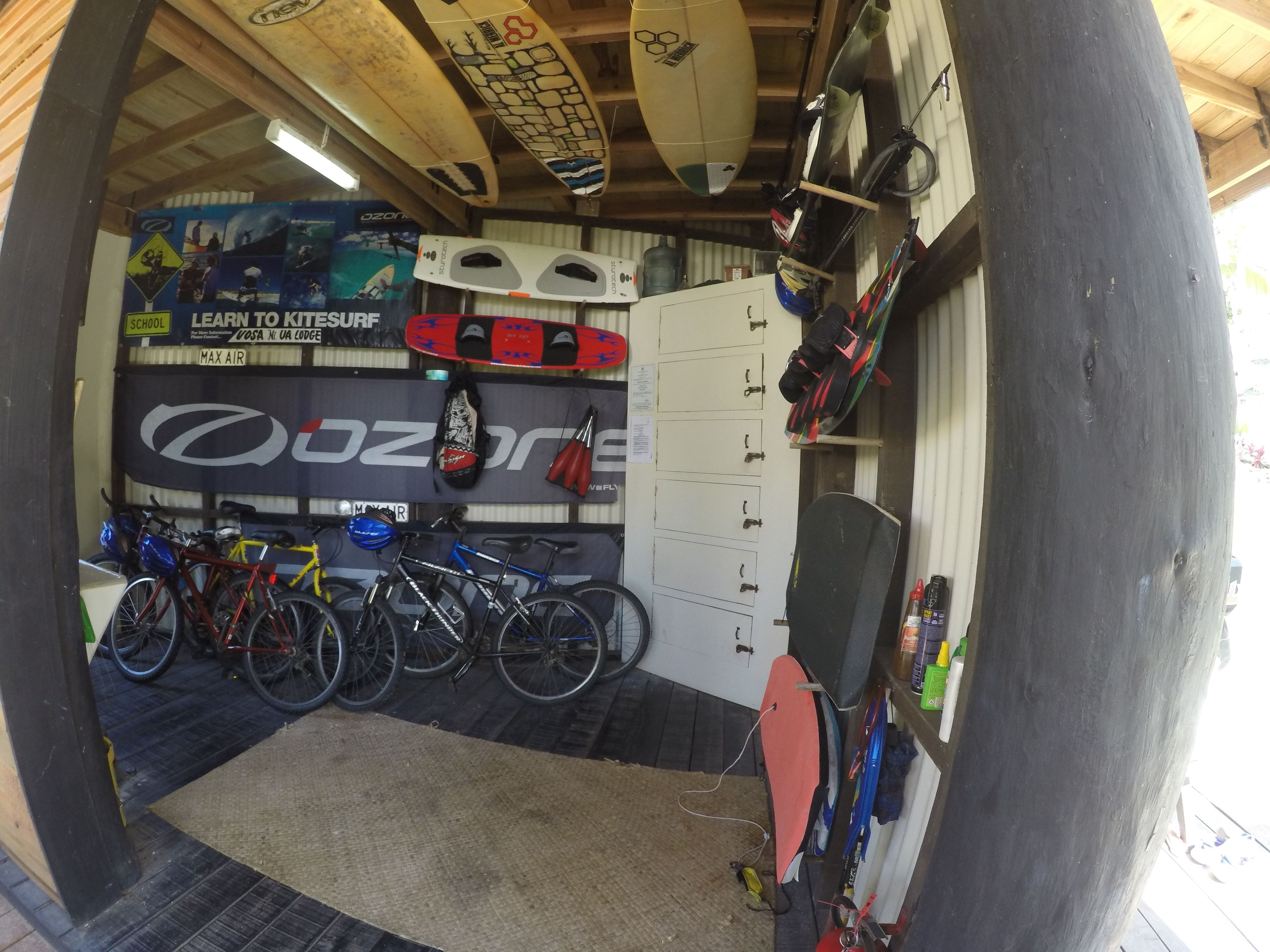 A storage room with surfboards, bicycles, and lockers.