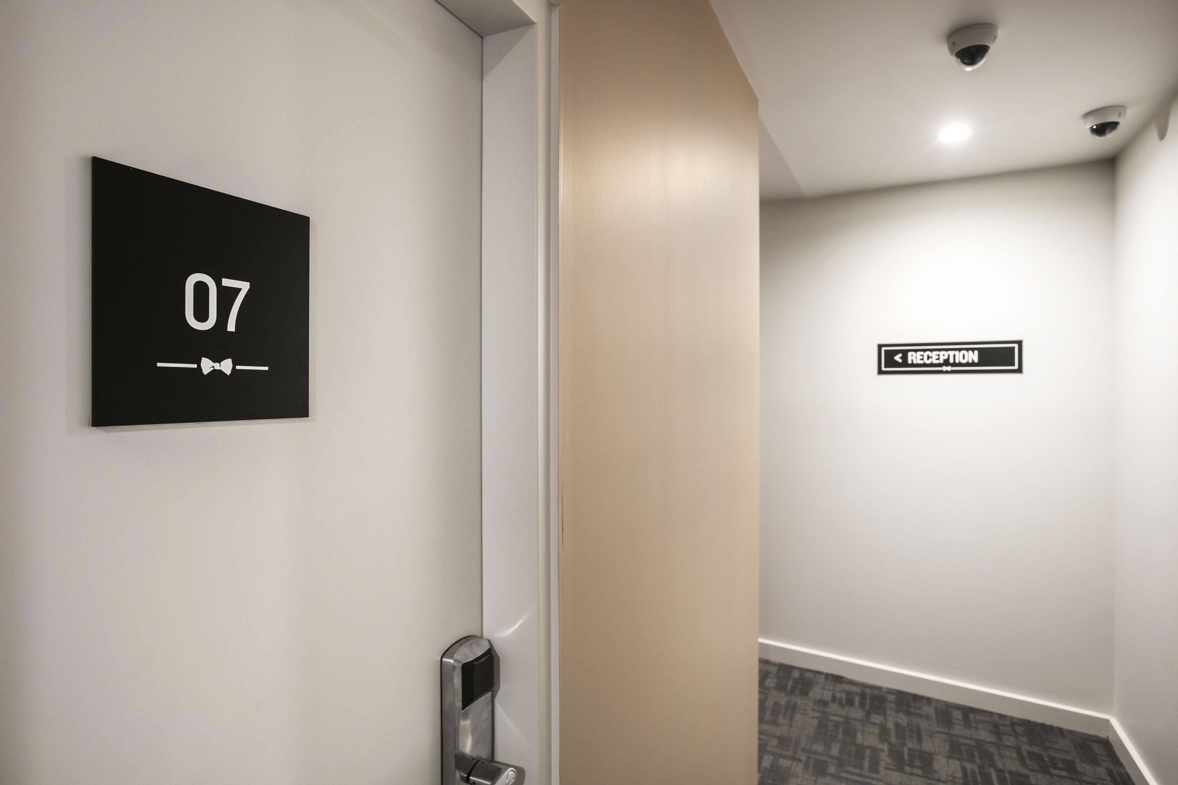 A hallway with a sign indicating room number 07 and a reception direction sign.