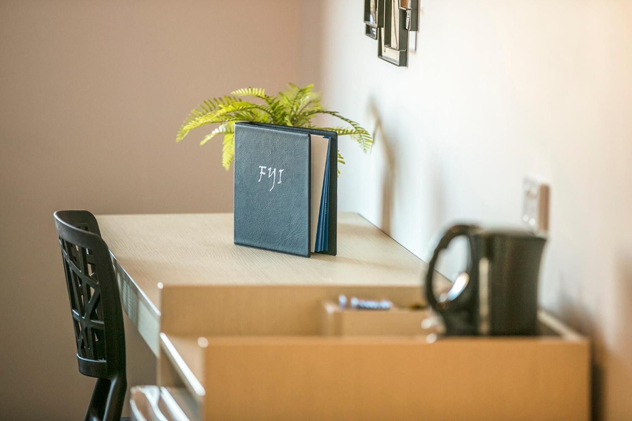 A desk with a dark blue book titled "FJI" and a potted plant.