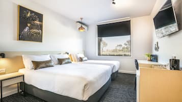 Une chambre d’hôtel avec deux lits, un bureau, une télévision et une fenêtre donnant sur un paysage agréable.