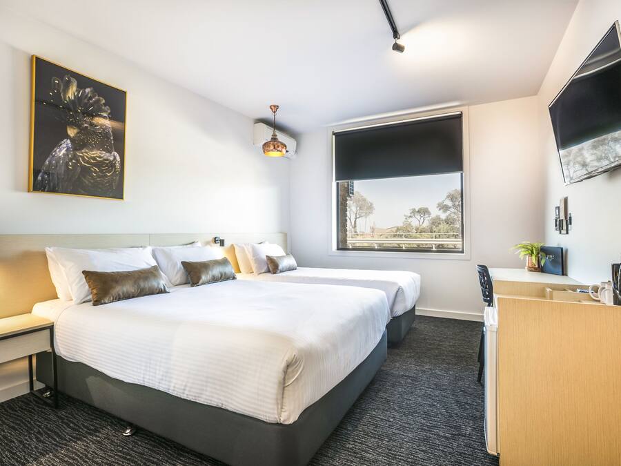 Une chambre d’hôtel avec deux lits, un bureau, une télévision et une fenêtre donnant sur un paysage agréable.