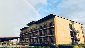 Un edificio de varios pisos con techo plano, ventanas grandes y una escalera de incendios a la derecha.