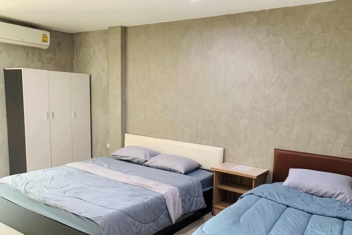 A bedroom with two beds, a wardrobe, and a small bedside table.