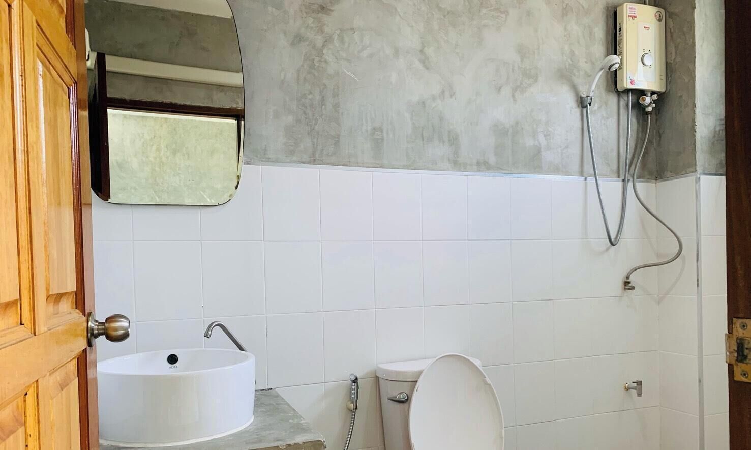 A bathroom with a bathtub, toilet, and a shower unit.