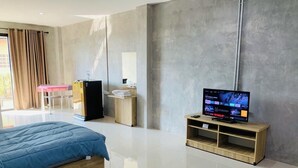 Una habitación de hotel moderna con cama, televisor, escritorio y refrigerador.