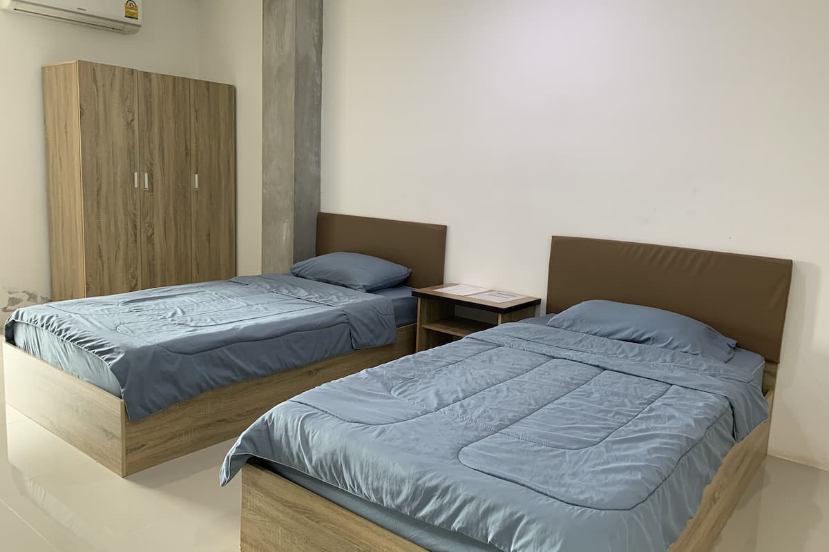 A bedroom with two beds, a wardrobe, and a small table.