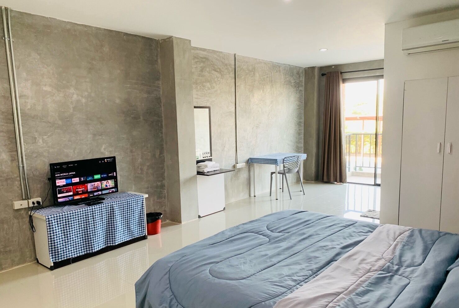 Ein modernes Hotelzimmer mit Bett, Fernseher, Schreibtisch und Kleiderschrank.