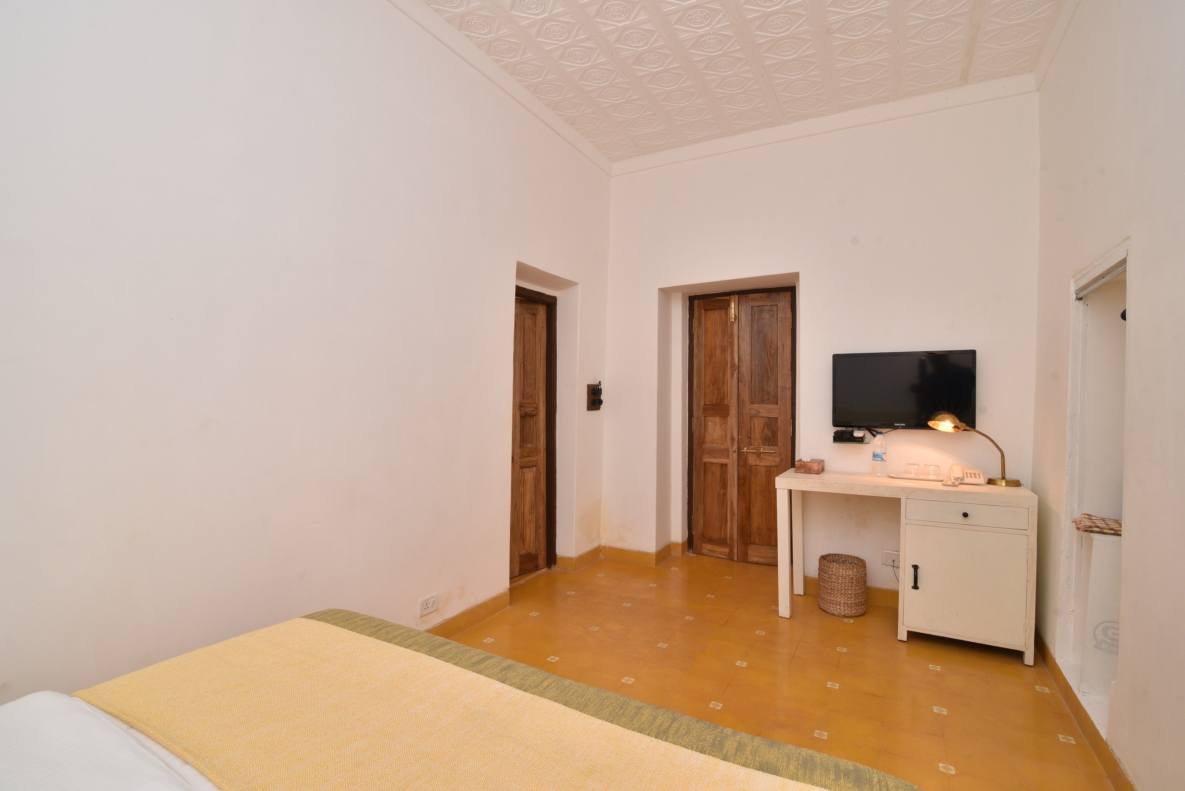 A bedroom with a bed, a desk, a television, and a cabinet.